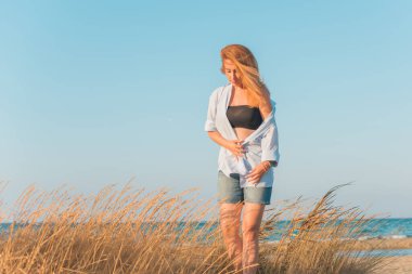 Deniz kenarında dinlenen dolgun kalçalı Avrupalı kadın mayo giydiğini gösterdi. 