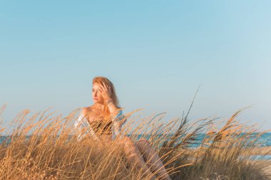Deniz kenarında dinlenen dolgun kalçalı Avrupalı kadın mayo giydiğini gösterdi. 