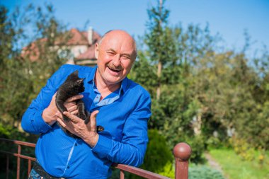 Küçük bir kedisi ve modern emeklilik hayatı olan aktif, kıdemli bir adam. Olgun erkek yaşam tarzı, pozitif duygular, evcil hayvan konsepti.