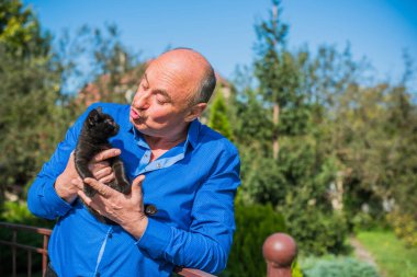 Küçük bir kedisi ve modern emeklilik hayatı olan aktif, kıdemli bir adam. Olgun erkek yaşam tarzı, pozitif duygular, evcil hayvan konsepti.