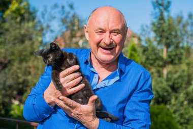 Küçük bir kedisi ve modern emeklilik hayatı olan aktif, kıdemli bir adam. Olgun erkek yaşam tarzı, pozitif duygular, evcil hayvan konsepti.