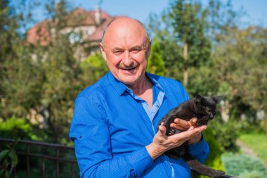 Küçük bir kedisi ve modern emeklilik hayatı olan aktif, kıdemli bir adam. Olgun erkek yaşam tarzı, pozitif duygular, evcil hayvan konsepti.