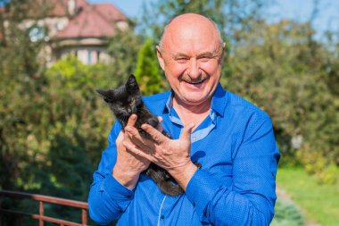 Küçük bir kedisi ve modern emeklilik hayatı olan aktif, kıdemli bir adam. Olgun erkek yaşam tarzı, pozitif duygular, evcil hayvan konsepti.