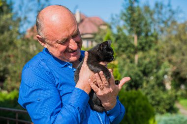 Küçük bir kedisi ve modern emeklilik hayatı olan aktif, kıdemli bir adam. Olgun erkek yaşam tarzı, pozitif duygular, evcil hayvan konsepti.