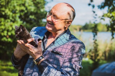 Küçük bir kedisi ve modern emeklilik hayatı olan aktif, kıdemli bir adam. Olgun erkek yaşam tarzı, pozitif duygular, evcil hayvan konsepti.