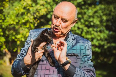 Küçük bir kedisi ve modern emeklilik hayatı olan aktif, kıdemli bir adam. Olgun erkek yaşam tarzı, pozitif duygular, evcil hayvan konsepti.