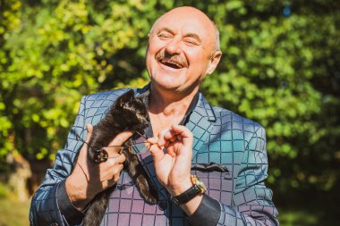 Küçük bir kedisi ve modern emeklilik hayatı olan aktif, kıdemli bir adam. Olgun erkek yaşam tarzı, pozitif duygular, evcil hayvan konsepti.