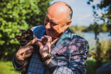 Küçük bir kedisi ve modern emeklilik hayatı olan aktif, kıdemli bir adam. Olgun erkek yaşam tarzı, pozitif duygular, evcil hayvan konsepti.