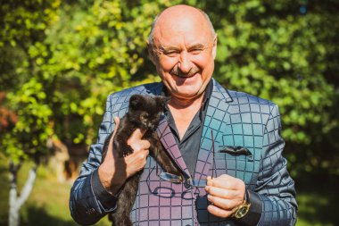 Küçük bir kedisi ve modern emeklilik hayatı olan aktif, kıdemli bir adam. Olgun erkek yaşam tarzı, pozitif duygular, evcil hayvan konsepti.