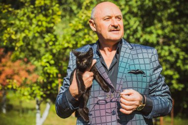 Küçük bir kedisi ve modern emeklilik hayatı olan aktif, kıdemli bir adam. Olgun erkek yaşam tarzı, pozitif duygular, evcil hayvan konsepti.