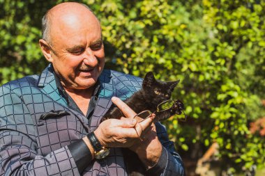 Küçük bir kedisi ve modern emeklilik hayatı olan aktif, kıdemli bir adam. Olgun erkek yaşam tarzı, pozitif duygular, evcil hayvan konsepti.
