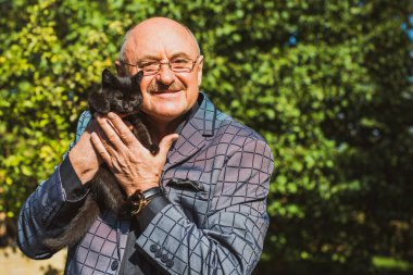 Küçük bir kedisi ve modern emeklilik hayatı olan aktif, kıdemli bir adam. Olgun erkek yaşam tarzı, pozitif duygular, evcil hayvan konsepti.