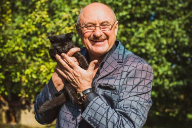 Küçük bir kedisi ve modern emeklilik hayatı olan aktif, kıdemli bir adam. Olgun erkek yaşam tarzı, pozitif duygular, evcil hayvan konsepti.