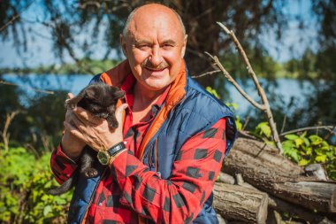 Küçük bir kedisi ve modern emeklilik hayatı olan aktif, kıdemli bir adam. Olgun erkek yaşam tarzı, pozitif duygular, evcil hayvan konsepti.