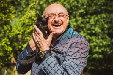 Küçük bir kedisi ve modern emeklilik hayatı olan aktif, kıdemli bir adam. Olgun erkek yaşam tarzı, pozitif duygular, evcil hayvan konsepti.