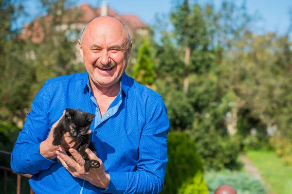 Küçük bir kedisi ve modern emeklilik hayatı olan aktif, kıdemli bir adam. Olgun erkek yaşam tarzı, pozitif duygular, evcil hayvan konsepti.