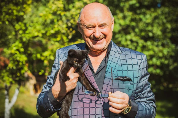 Küçük bir kedisi ve modern emeklilik hayatı olan aktif, kıdemli bir adam. Olgun erkek yaşam tarzı, pozitif duygular, evcil hayvan konsepti.