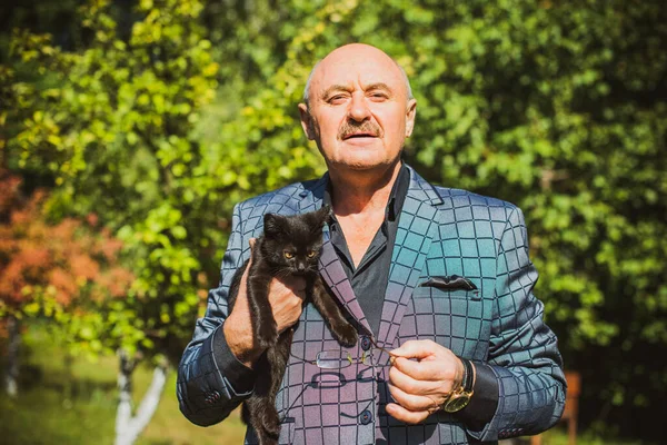 Küçük bir kedisi ve modern emeklilik hayatı olan aktif, kıdemli bir adam. Olgun erkek yaşam tarzı, pozitif duygular, evcil hayvan konsepti.