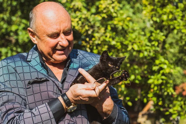 Küçük bir kedisi ve modern emeklilik hayatı olan aktif, kıdemli bir adam. Olgun erkek yaşam tarzı, pozitif duygular, evcil hayvan konsepti.