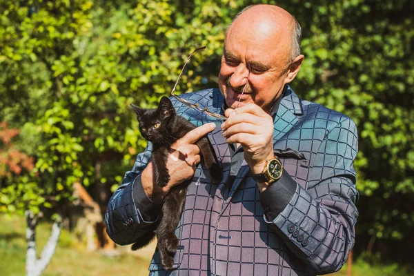 Küçük bir kedisi ve modern emeklilik hayatı olan aktif, kıdemli bir adam. Olgun erkek yaşam tarzı, pozitif duygular, evcil hayvan konsepti.