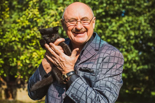 Küçük bir kedisi ve modern emeklilik hayatı olan aktif, kıdemli bir adam. Olgun erkek yaşam tarzı, pozitif duygular, evcil hayvan konsepti.