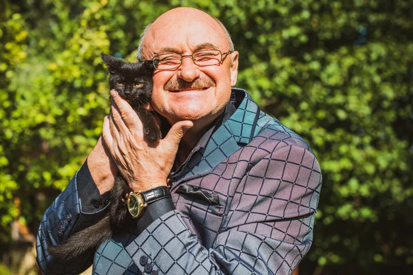 Küçük bir kedisi ve modern emeklilik hayatı olan aktif, kıdemli bir adam. Olgun erkek yaşam tarzı, pozitif duygular, evcil hayvan konsepti.