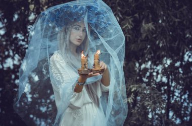 Bride making magic of candles, magical attributes, herbs and flowers, Slavic/ Wicca rituals and esoteric concept