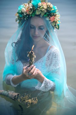 Bride making magic of candles, magical attributes, herbs and flowers, Slavic/ Wicca rituals and esoteric concept