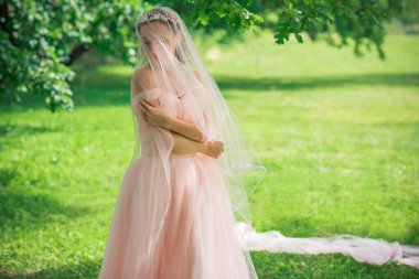 Pembe pastel gelinlik içinde zarif genç gelin, şık bir koleksiyon.