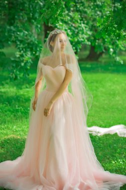 Pembe pastel gelinlik içinde zarif genç gelin, şık bir koleksiyon.