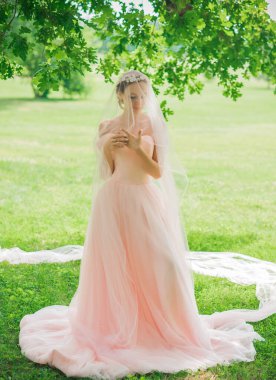 Pembe pastel gelinlik içinde zarif genç gelin, şık bir koleksiyon.