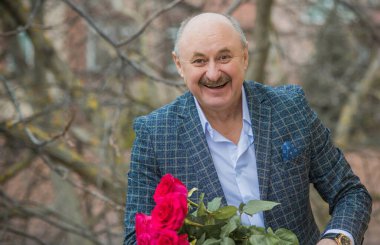 Yaşlı, mutlu, elinde bir buket çiçekle bir randevuyu bekleyen yaşlı adam. Olgun insanların yaşam tarzı