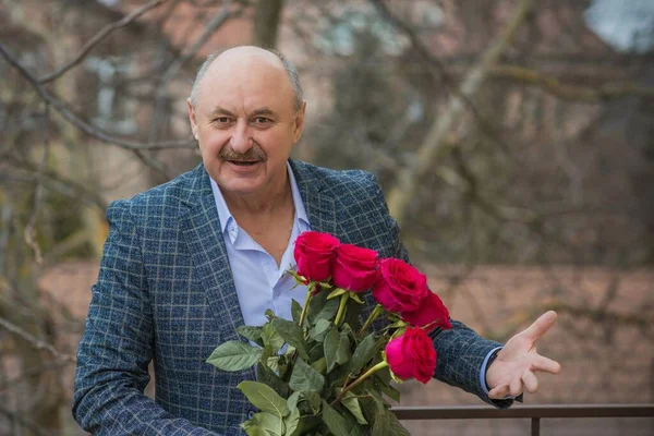 Older happy Senior man with a bouquet of flowers waiting on a date. Mature people lifestyle