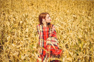 Kırmızı ekoseli, kırmızı ayakkabılı, güneşli sonbahar gününde tarlada dinlenen tatlı kızıl saçlı kız. Şehir kibrinin dışında rahatlık ve uyum kavramı.