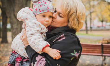 Yetişkin bir anne, parkta küçük bir kızla yürüyor ve eğleniyor. 40 yıl sonra geç annelik.