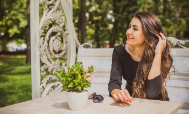 Doğa, yaz tatili, tatil ve insanların konsepti. Parktaki genç Arap kadın iyi bir hayat düşlüyor ve anın tadını çıkarıyor.