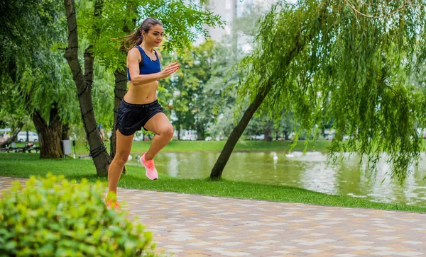 緑豊かな緑の都市公園で外で行使美しいブルネットの女性のフィットネスの女の子 公園でスポーツトップジョギングの女性 健康的な女の子のライフスタイルの背景とともにコピースペース — ストック写真