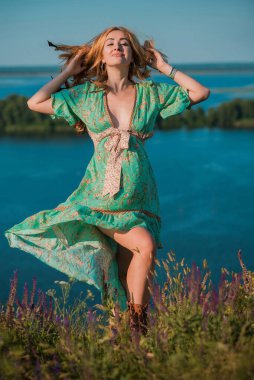 Klasik Boho tarzı, saten elbiseli ve gün batımında çizmeli bir kız, şık kıyafetler ve detaylar. Yaz stili