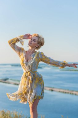 Sarışın romantik kadın pofuduk elbiseli, güzel bayan kıyafeti, gün batımında çayırdaki kız.