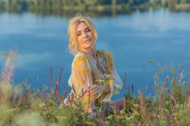 Sarışın romantik kadın pofuduk elbiseli, güzel bayan kıyafeti, gün batımında çayırdaki kız.