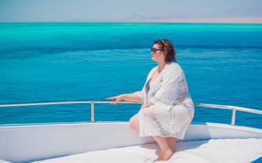 Tombul orta yaşlı kadın yatta dinleniyor, olgun kadınlar için yaşam tarzı, büyük beden kıyafetler. 