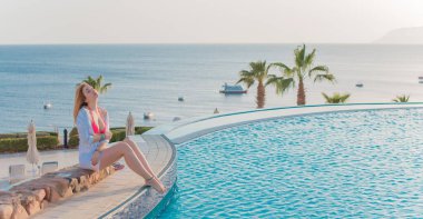 Tropik tatil köyünde güzel bir rahatlama, tatil konsepti, havuzda güneşlenen güzel bir kadın.