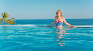 Tropik tatil köyünde güzel bir rahatlama, tatil konsepti, havuzda güneşlenen güzel bir kadın.