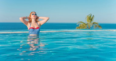 Tropik tatil köyünde güzel bir rahatlama, tatil konsepti, havuzda güneşlenen güzel bir kadın.