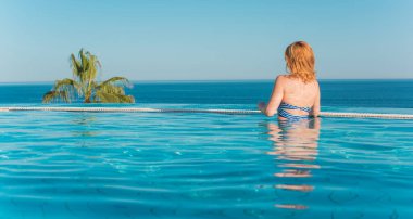 Tropik tatil köyünde güzel bir rahatlama, tatil konsepti, havuzda güneşlenen güzel bir kadın.