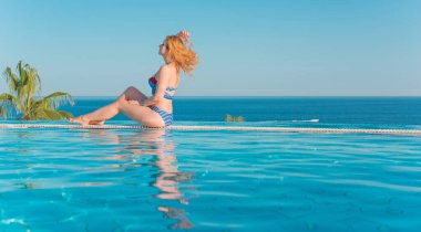 Tropik tatil köyünde güzel bir rahatlama, tatil konsepti, havuzda güneşlenen güzel bir kadın.