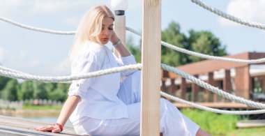 Sarışın, iri yarı, Amerikan ya da Avrupalı görünümlü bir kadın golf sahasında yürüyor, hayattan zevk alıyor. Aşırı kilolu, şık giyinmiş beyaz bir bayan. Doğal güzellik.