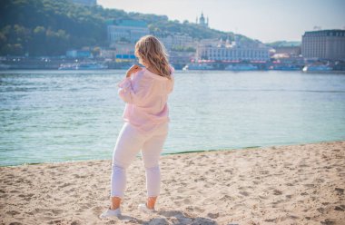 Artı plajda Avrupalı sarışın bir kadın, tatilde, hayatın tadını çıkarıyor, yürüyor. İnsanların hayatı XI boyutunda, mutlu doğal güzel bir bayan. Aşırı kilolu kavramı