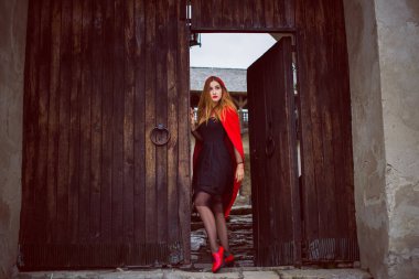 Cadılar Bayramı kavramı. Küçük kırmızı başlıklı güzel ve basit bir kostüm. Sisli ormandaki gizemli kukuletalı figür. Kırmızı yağmurluklu kız. Kostümlü Masal Kırmızı Başlıklı Kız