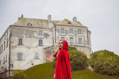 Cadılar Bayramı kavramı. Küçük kırmızı başlıklı güzel ve basit bir kostüm. Sisli ormandaki gizemli kukuletalı figür. Kırmızı yağmurluklu kız. Kostümlü Masal Kırmızı Başlıklı Kız